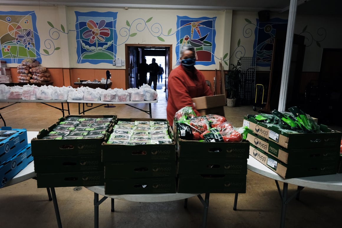Volunteers stocking a food pantry with boxes of fresh produce and packaged goods in Kensington.